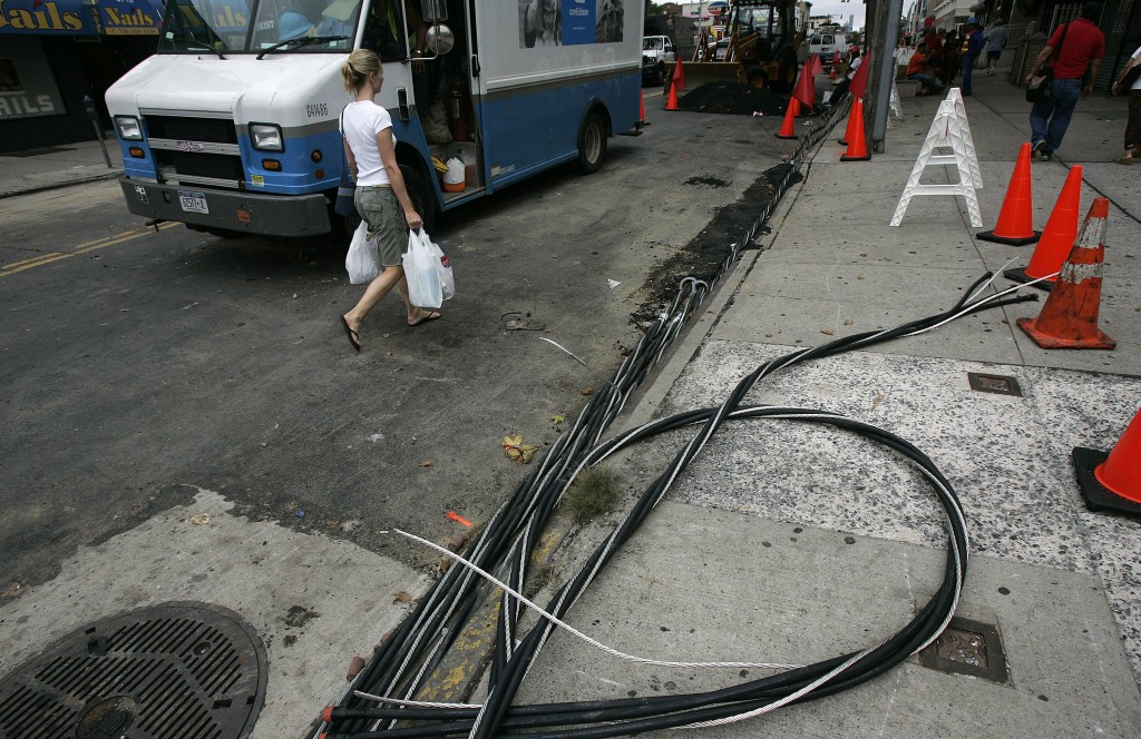 NEW YORK - JULY 23:  A woman walks past power lines on the sidewalk as workers try to restore electrical service July 23, 2006 in the Queens borough of New York City. Many Con Edison and other electrical workers have been working long hours attempting to restore power to thousands of people that were left without electricity after a blackout a week ago.  (Photo by Chris Hondros/Getty Images)